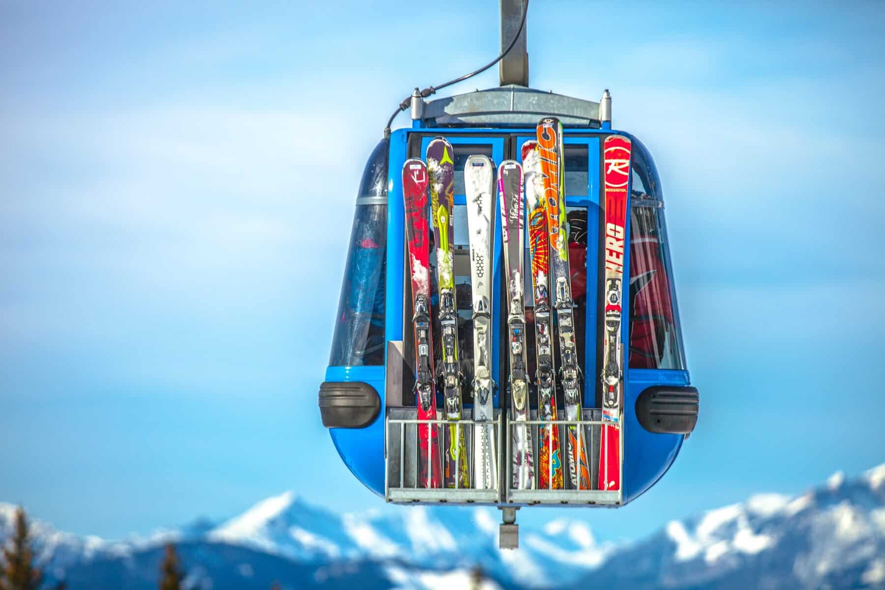Gondola in ski resort in europe with ski hire through monsguide. Beginner, intermediate and advanced equipment rental skis shown with fresh snow mountain backdrop. From Sauze d'Oulx to Mayrhofen, Italy to Austria, this generic image of ski lifts and skiers.