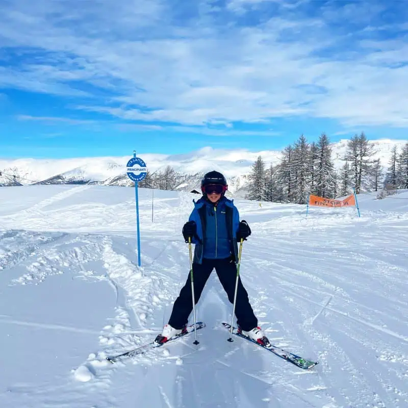 A beginner skier in Sauze d'Oulx on a blue run, during his ski lesson with Ski School Sportinia. Via Lattea Family tuition. Snowboard and ski lessons in Sauze d'Oulx on blue slope